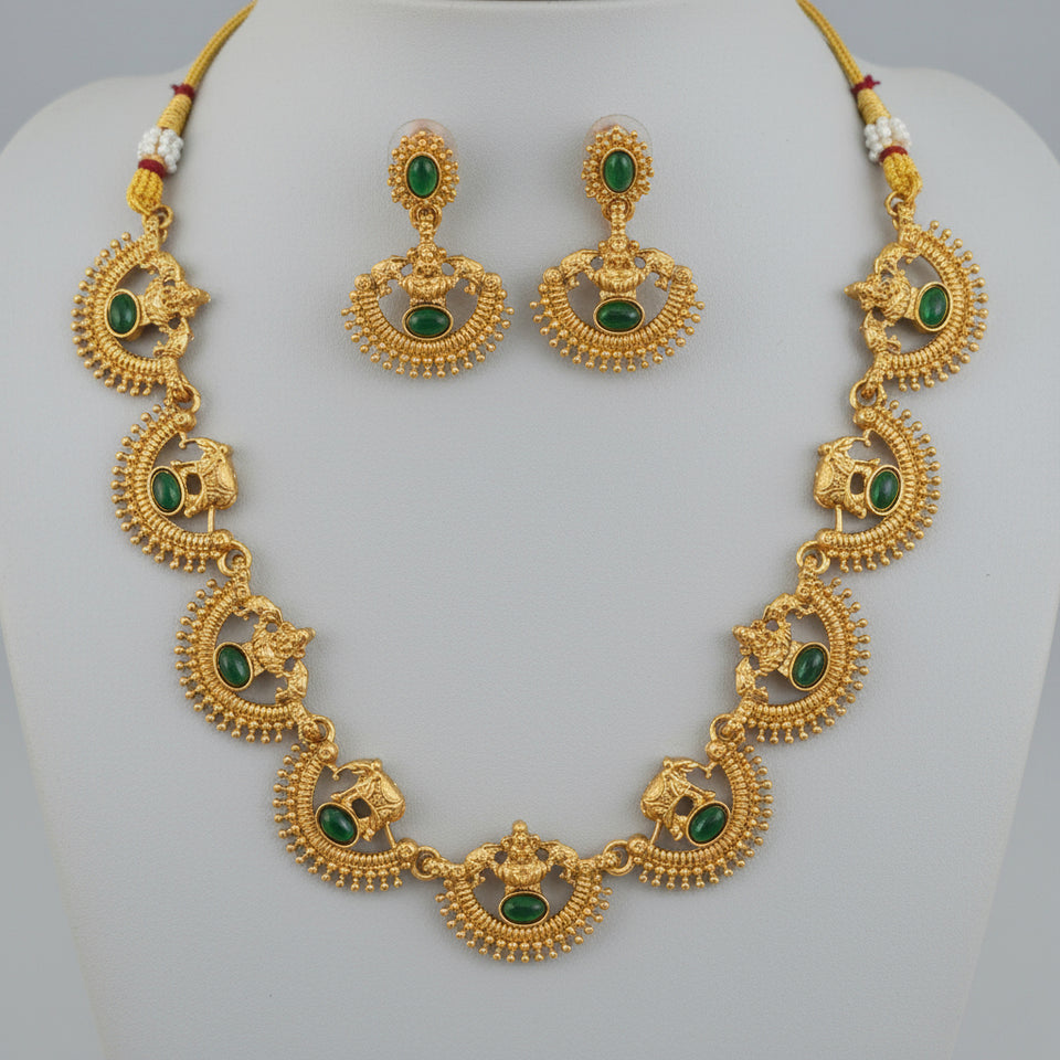 Gold jewelry set with green stones held in a hand against a natural background