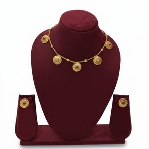 Gold necklace and earrings on a green velvet stand against a white background