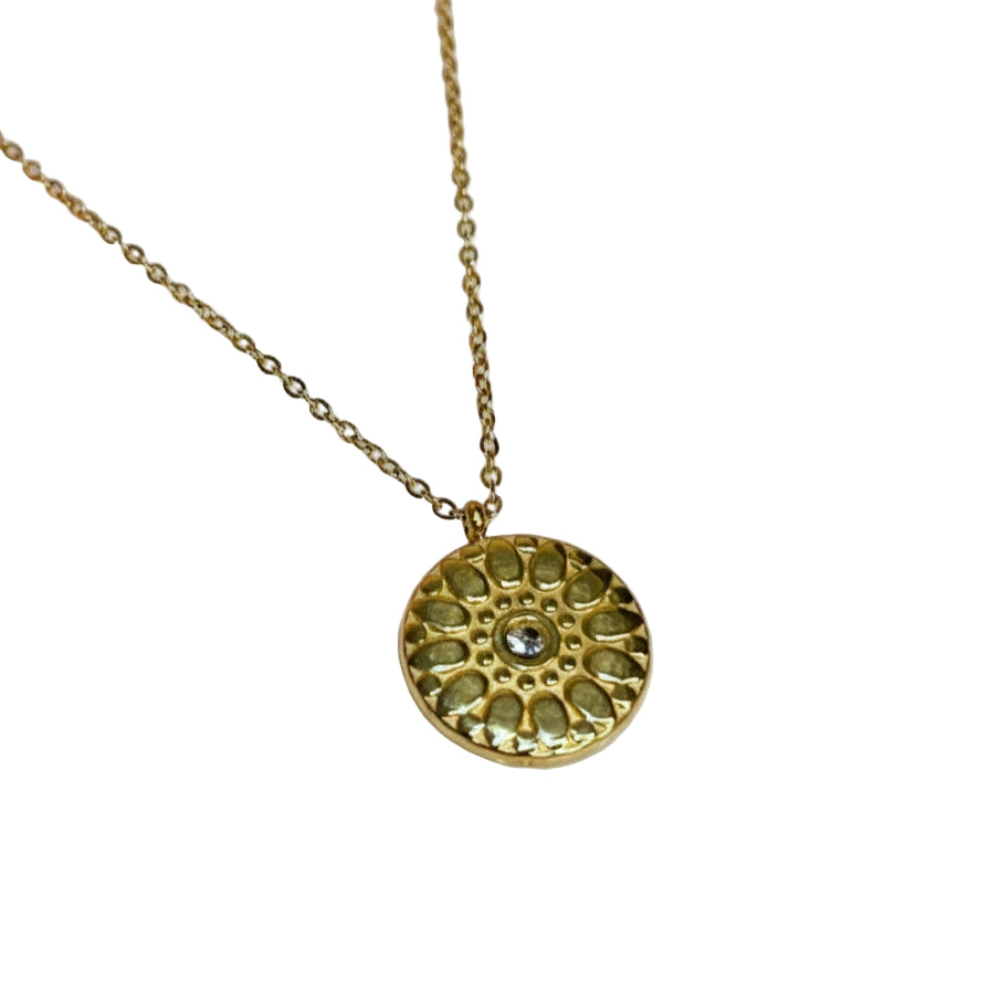 Gold necklace with a circular pendant on a white background