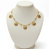 Gold necklace with circular pendants on a green mannequin bust.