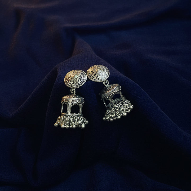 Pair of silver earrings on a black fabric background