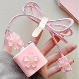 Pink floral charging cable with a clip held by a hand on a light gray background