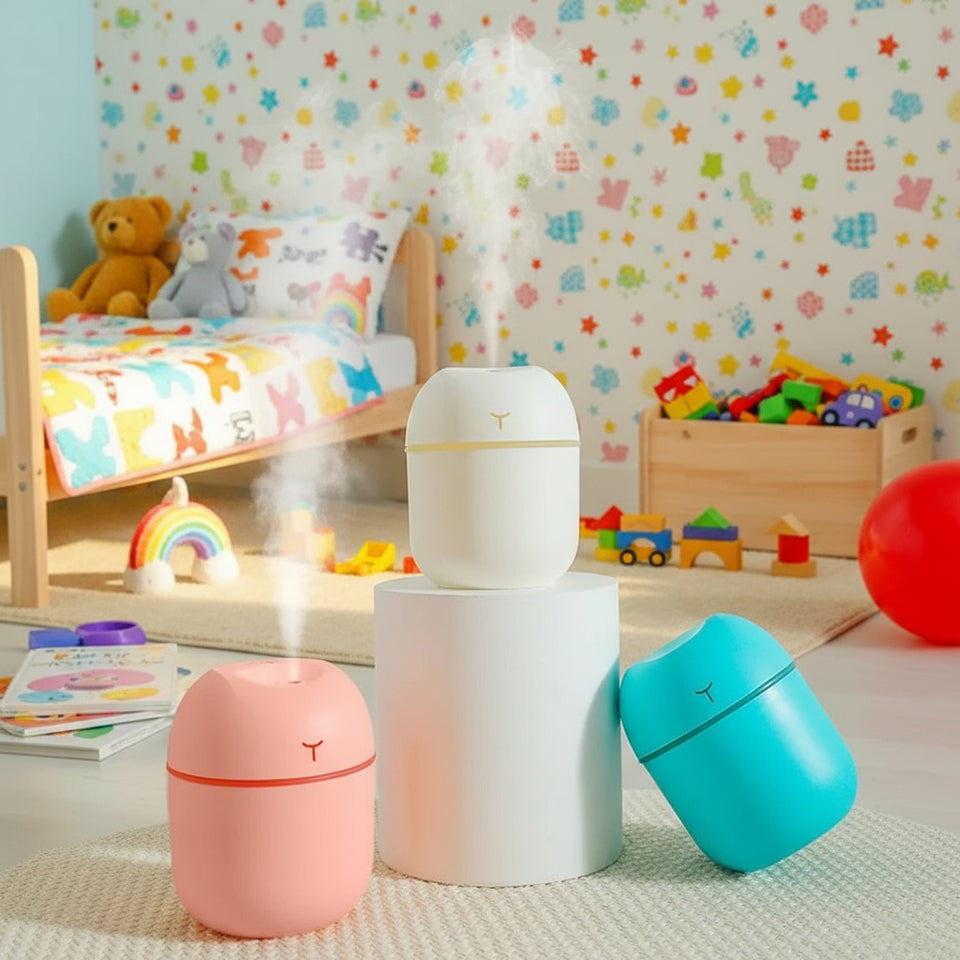 Three small humidifiers in white, pink, and blue on a textured surface with a light background.