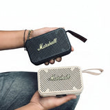 Two Marshall portable speakers held by a person inside a vehicle.