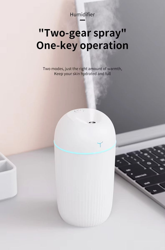 White humidifier on a desk with a laptop, text about two-gear spray and one-key operation.